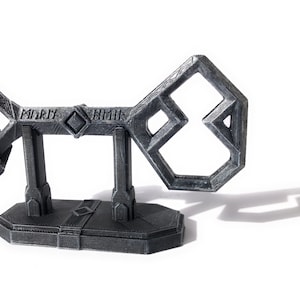 May include: A silver-colored, 3D printed key with a complex design, featuring the word "remark" on the top. The key is displayed on a matching stand.