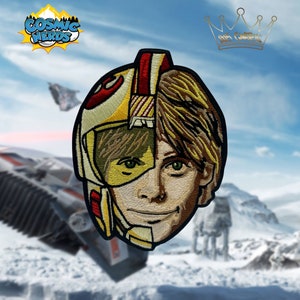 May include: Embroidered patch featuring a split image of Luke Skywalker from Star Wars. One side shows his face, the other shows his X-Wing pilot helmet. The patch is yellow, red, and brown.