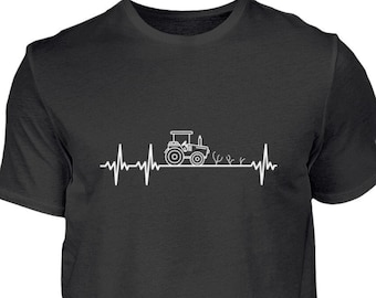 Op de afbeelding: Zwart T-shirt met een witte afbeelding van een tractor die door een veld rijdt met een hartslaglijn erboven.