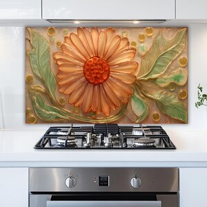 May include: A decorative kitchen backsplash featuring a large, embossed orange flower with a red center and green leaves. The artwork is set against a neutral background with yellow accents, adding a touch of nature to the kitchen.