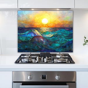 A stained-glass style backsplash featuring an ocean sunset with rolling waves is set in a modern white kitchen. It is positioned behind a gas cooktop, flanked by jars of ingredients and a potted plant.