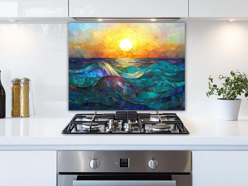 A stained-glass style backsplash featuring an ocean sunset with rolling waves is set in a modern white kitchen. It is positioned behind a gas cooktop, flanked by jars of ingredients and a potted plant.