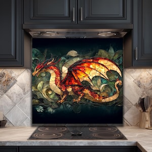 May include: A stained glass-style artwork featuring a red and orange dragon with large wings. The dragon is set against a dark background with green and gold accents. The artwork is mounted above a black stovetop.
