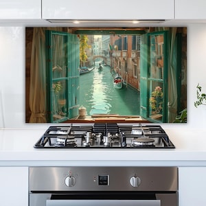 May include: A decorative kitchen backsplash featuring a vibrant image of a Venetian canal scene viewed through an open window. The artwork showcases a gondola, buildings, and turquoise water, framed by green window shutters and sheer curtains.