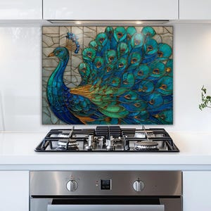 Stained glass-style kitchen backsplash featuring a vibrant blue and teal peacock with a sprawling feathered tail. The artistic panel is mounted behind a stainless steel gas stove in a bright, modern white kitchen with minimalist cabinets.