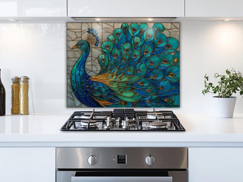 Stained glass-style kitchen backsplash featuring a vibrant blue and teal peacock with a sprawling feathered tail. The artistic panel is mounted behind a stainless steel gas stove in a bright, modern white kitchen with minimalist cabinets.