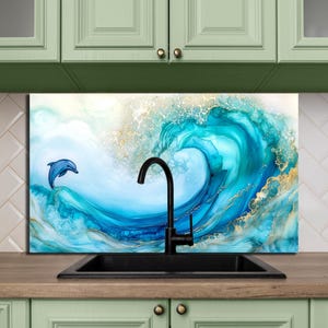 May include: An abstract art panel depicting a wave in shades of blue and gold, with a dolphin leaping from the water. The artwork is positioned above a black sink and tap, set against green kitchen cabinets.