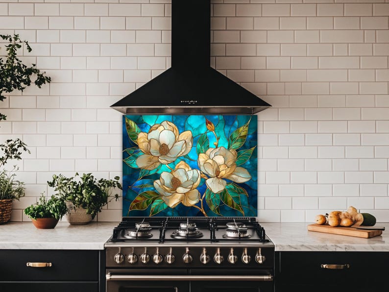 Stained glass style backsplash featuring three cream magnolias on a vibrant turquoise background, installed behind a black gas range in a white subway-tiled kitchen with dark cabinetry.