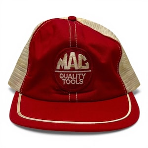 Może przedstawiać: Czerwono-beżowa czapka typu trucker z wyhaftowanym napisem "MAC QUALITY TOOLS". Czapka ma czerwony panel przedni i daszek z beżowym tyłem z siatki. Daszek jest obrysowany cienkim białym obramowaniem.