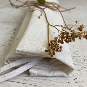 Może przedstawiać: Biały lniany ręcznik do herbaty złożony i związany sznurkiem i suszoną gałązką kwiatów.