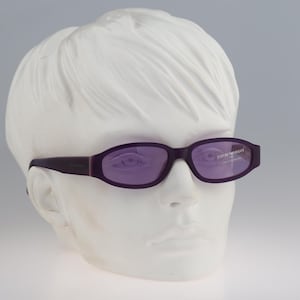 Puede incluir: Gafas de sol moradas con lentes de color morado oscuro y el texto "EMPORIO ARMANI" en la lente derecha.