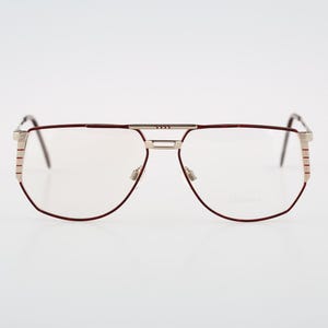 May include: A pair of silver and burgundy eyeglasses with a rectangular frame.