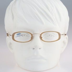 May include: A pair of brown, rectangular-shaped eyeglasses with a silver frame. The glasses have a blue label that reads "Salo Stainless Steel".
