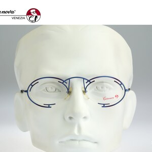 May include: Blue metal framed glasses with a round lens shape. The glasses are on a white mannequin head. The brand name "Casanova" is printed on the right lens.