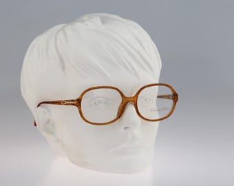 Puede incluir: Gafas con patrón de carey marrón y forma de montura rectangular redondeada. Las patillas presentan un detalle de metal en tono dorado con el logotipo CD. El cristal derecho está grabado con el texto Christian Dior en letra cursiva.