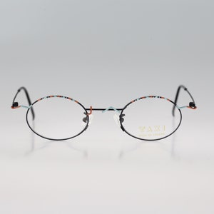 May include: Black round-framed glasses with a blue and orange patterned trim. The glasses say "Taxi Made in Japan" on the right lens.