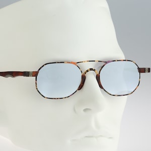Puede incluir: Un par de gafas de sol con estampado de carey, detalles plateados y lentes espejados.