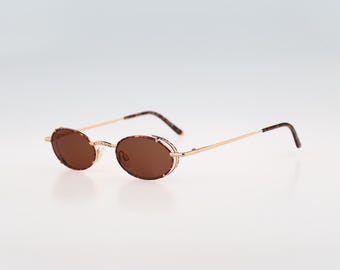 May include: Gold-rimmed oval sunglasses with brown lenses. The frame is a tortoise shell pattern.