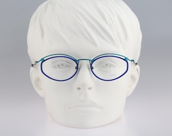 May include: Oval-shaped eyeglasses featuring a dual-tone metal frame with a deep blue lower rim and a teal upper rim. The thin metal temples connect to the frame at the outer edges, and the clear lenses are held by a delicate bridge structure.