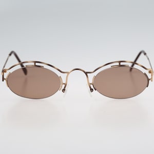 May include: A pair of gold-toned oval-shaped sunglasses with brown lenses.