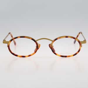 May include: A pair of gold-rimmed oval eyeglasses with tortoise shell frames.