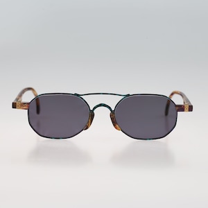 Puede incluir: Un par de gafas de sol ovaladas con lentes grises oscuros y un marco de color turquesa y marrón.