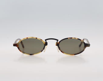 May include: Tortoise shell oval sunglasses with brown lenses.
