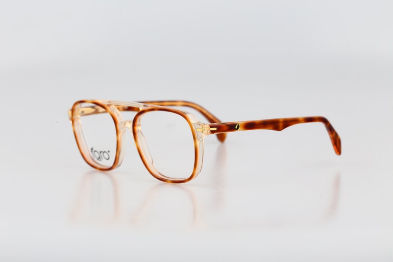 May include: Tortoiseshell eyeglasses with clear lenses and a gold accent on the bridge.