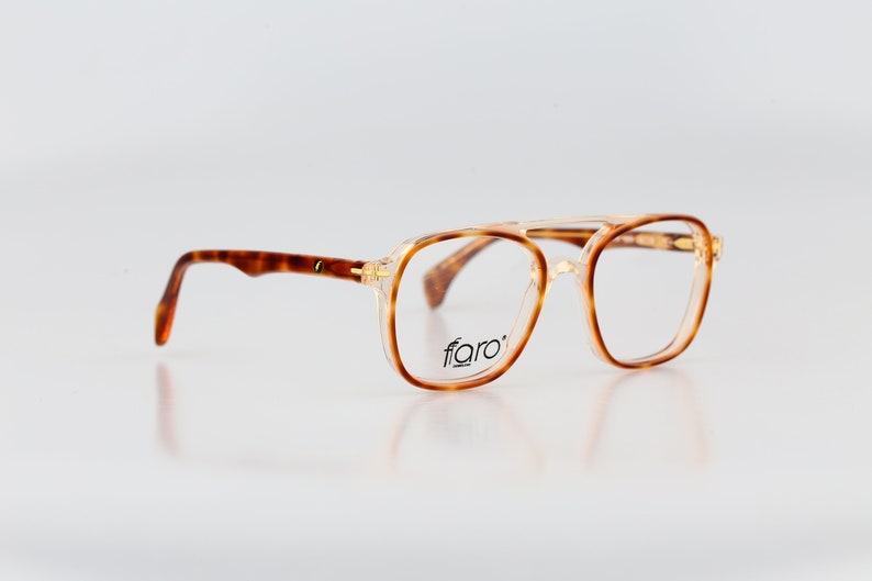 May include: Tortoise shell eyeglasses with gold accents and a clear lens. The brand name "fiaro" is printed on the frame.