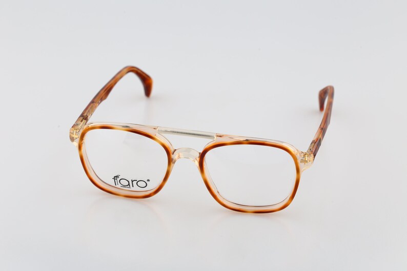 May include: Tortoise shell eyeglasses with a clear frame and the word "faro" printed on the right lens.