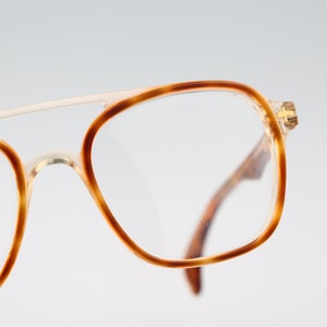 May include: Close-up of a pair of tortoiseshell eyeglasses with a gold metal bridge. The glasses have a clear lens and the brand name "faro" is printed on the left temple.