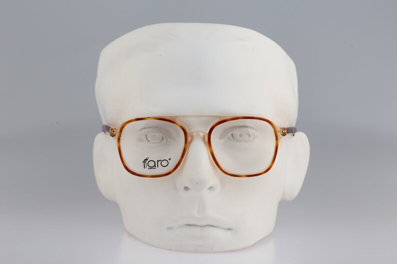 May include: Brown tortoiseshell eyeglasses with a square frame and clear lenses. The glasses have the word "faro" printed on the right lens.