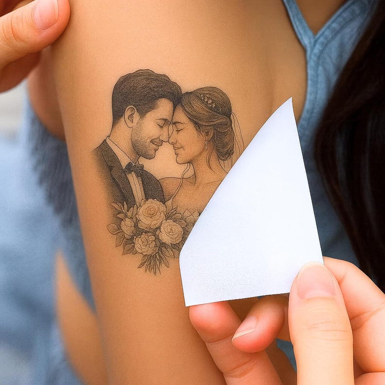 May include: A black and white tattoo of a couple embracing, with a bouquet of roses. The man is wearing a tuxedo and the woman is wearing a wedding dress. A white piece of paper is being held over the tattoo.