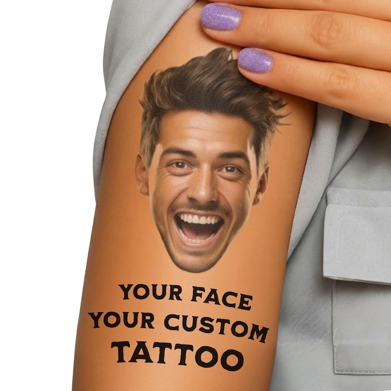 May include: A temporary tattoo featuring a smiling man's face. The tattoo is printed on a light orange skin tone and includes the text "YOUR FACE YOUR CUSTOM TATTOO" in bold, black letters. The image is of a person's arm.
