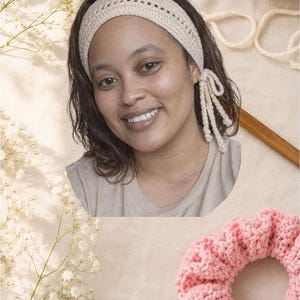 May include: A woman wearing a cream-colored crocheted headband with a bow detail. A pink crocheted scrunchie is in the foreground. The background includes yarn and a wooden crochet hook, suggesting handmade accessories.