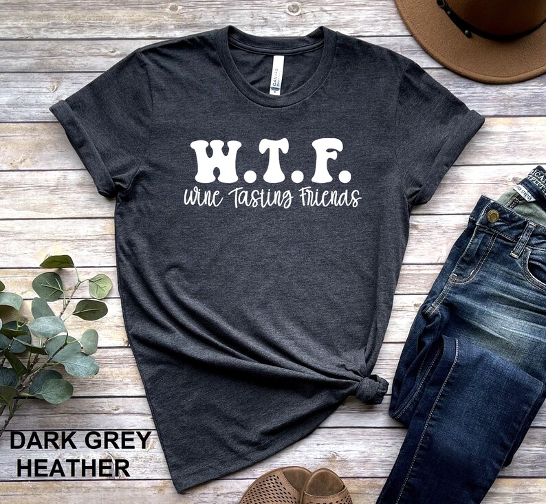 K&ouml;nnte beinhalten: Dunkelgraues T-Shirt mit Melange-Effekt und wei&szlig;em Text, der "W.T.F. wine Tasting Friends" lautet.
