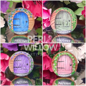 May include: Four painted rocks with whimsical door designs. Each rock features a different coloured door with ivy and flowers. The doors are painted in shades of blue, green, purple, and pink. Each rock has a black chalkboard sign with the word "Welcome" written in white chalk.