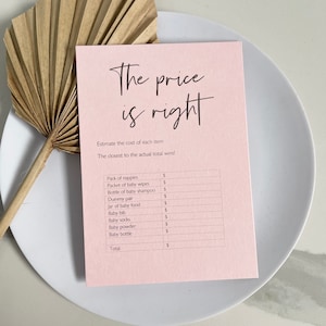 May include: A pink printable game card with the text "The price is right" and a list of baby items with a pound sign next to each item. The items include: pack of nappies, packet of baby wipes, bottle of baby shampoo, dummy pair, jar of baby food, baby bib, baby socks, baby powder, baby bottle, and total.