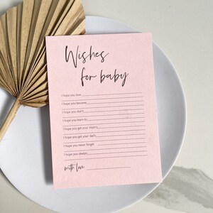 May include: A pink card with the text "Wishes for baby" at the top. The card has lines for writing wishes for a new baby.