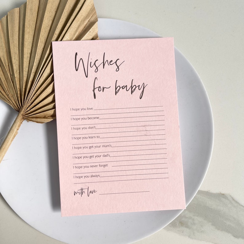 May include: A pink card with the text "Wishes for baby" at the top. The card has lines for writing wishes for a new baby.