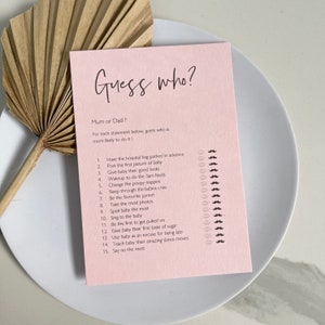 May include: Pink card game with the title "Guess who?" and a list of 15 questions about new parents. The questions are designed to determine if the statement is more likely to be done by the mother or father.  Each question has a row of pink lips and brown moustaches to indicate the answer.