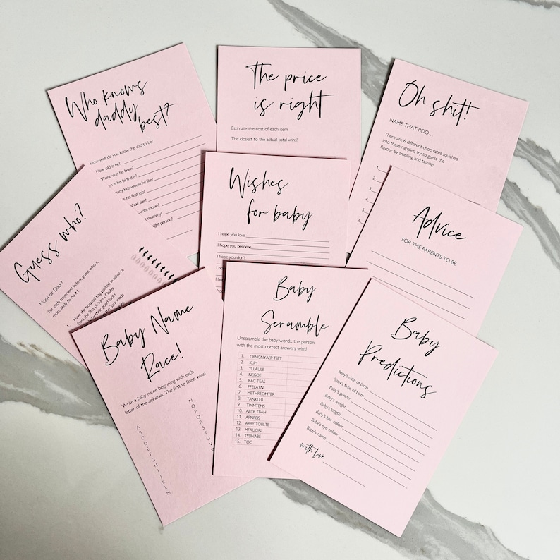 May include: Pink baby shower game cards with black text. The cards include games like "Who Knows Daddy Best?", "Guess Who?", "Baby Name Race", "Baby Scramble", "Wishes for Baby", "Baby Predictions", "Oh Shit! Name That Poo", and "Advice for the Parents to Be".