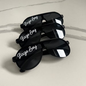 May include: Three black aviator sunglasses with the text "Page Boy" in white cursive lettering on the lenses.