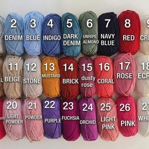 May include: A collection of 27 yarn skeins in various colors, each labeled with a number and color name. Colors range from grey, blue, and red to pink, purple, and white. The image is well-lit, showcasing the texture and hues of the yarn.