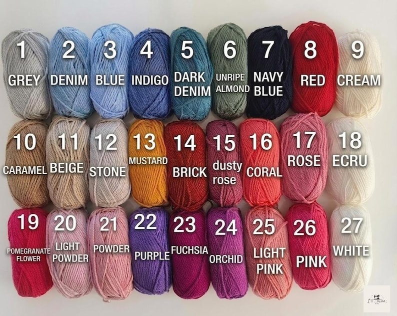 May include: A collection of 27 yarn skeins in various colors, each labeled with a number and color name. Colors range from grey, blue, and red to pink, purple, and white. The image is well-lit, showcasing the texture and hues of the yarn.