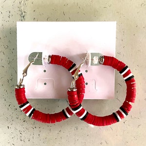 May include: A pair of red and white hoop earrings with a silver clasp. The earrings are made of stacked round beads.