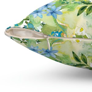 Op de afbeelding: Een groene en blauwe bloemen kussenhoes met een rits. De kussenhoes heeft een aquarel ontwerp van bloemen en bladeren.
