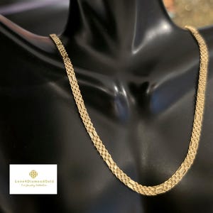 May include: A gold chain necklace featuring a woven, multi-strand link design with a flat, flexible structure. The necklace is displayed on a black mannequin bust. A small white rectangular logo with the text Love4DiamondGold is visible.
