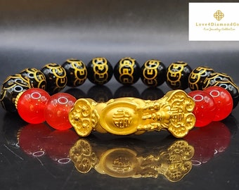May include: A black and red beaded bracelet with a gold charm in the shape of a mythical creature. The charm has Chinese characters on it.