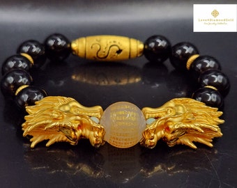 Könnte beinhalten: Ein Armband aus schwarzen Onyxperlen mit goldenen Drachenkopf-Anhängern an beiden Seiten einer klaren Kristallperle mit goldenen Schriftzeichen. Das Armband hat außerdem eine goldene Perle mit einem Drachenmotiv.